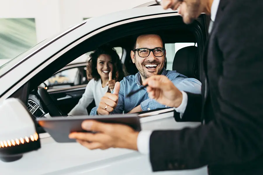 A couple smiling inside of a car.
