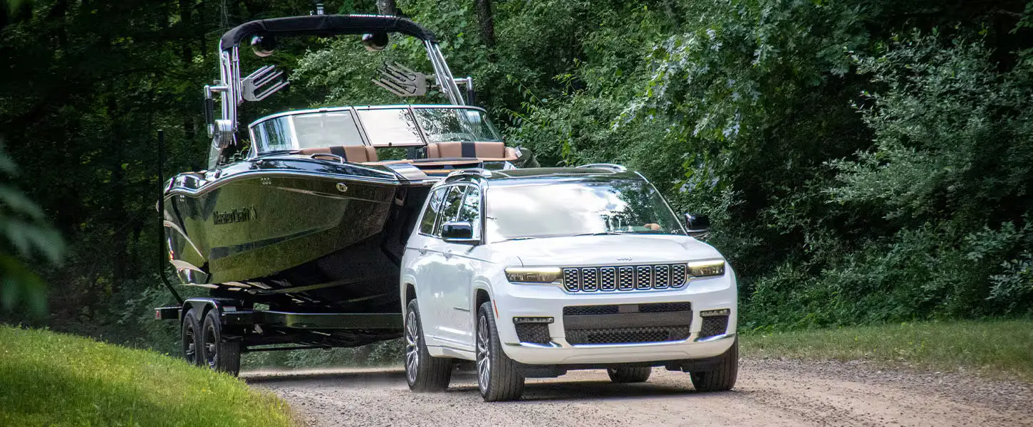 A white suv pulling a boat.