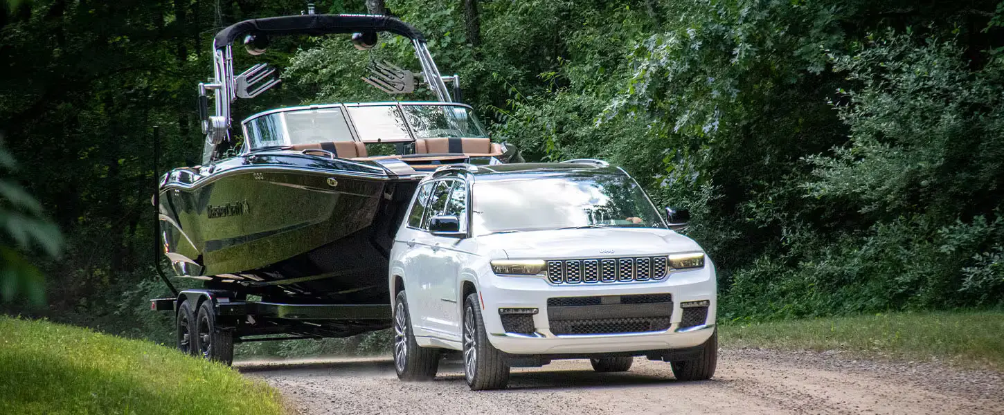 A white suv pulling a boat.