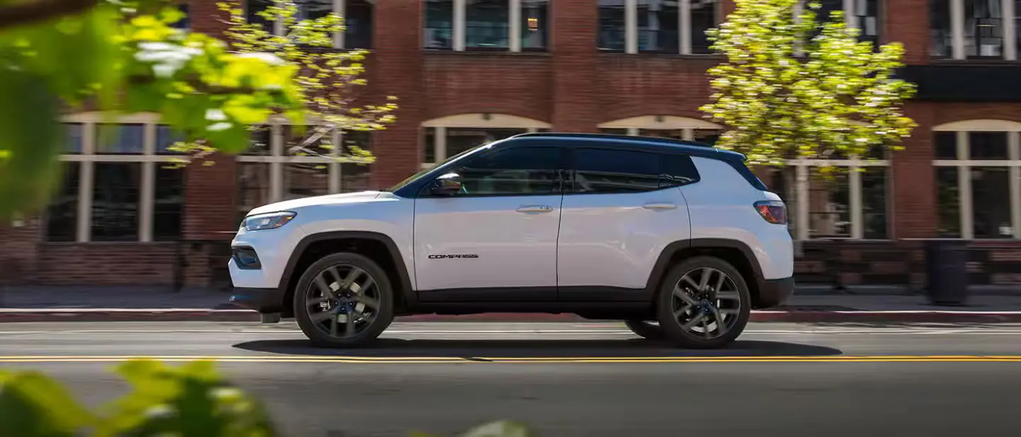 2026 jeep compass in white driving in a suburban setting