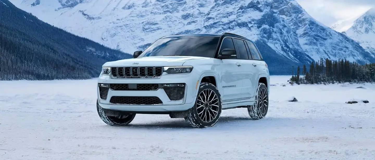 A white jeep grand cherokee sitting parked in the snow.