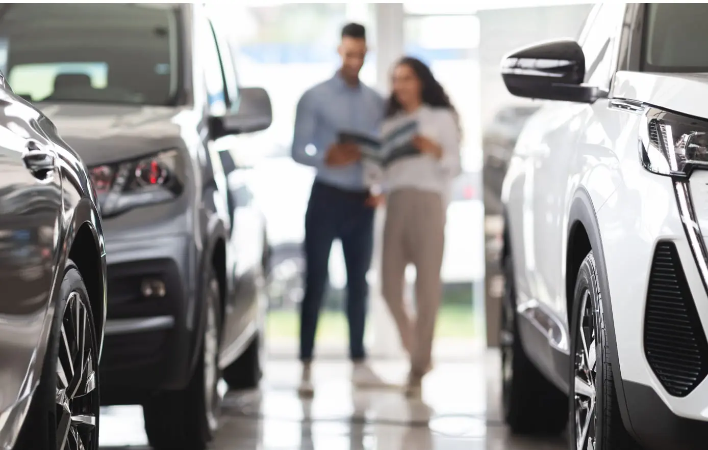 Couple browsing vehicles together in a dealership showroom.