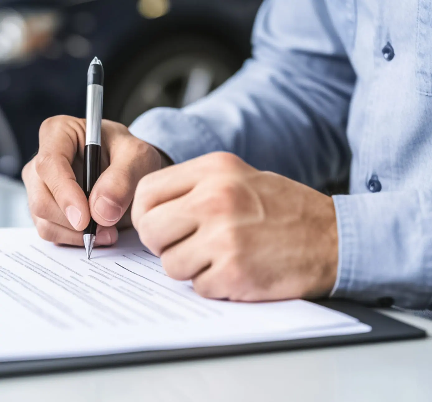 Person signing paperwork with a pen.