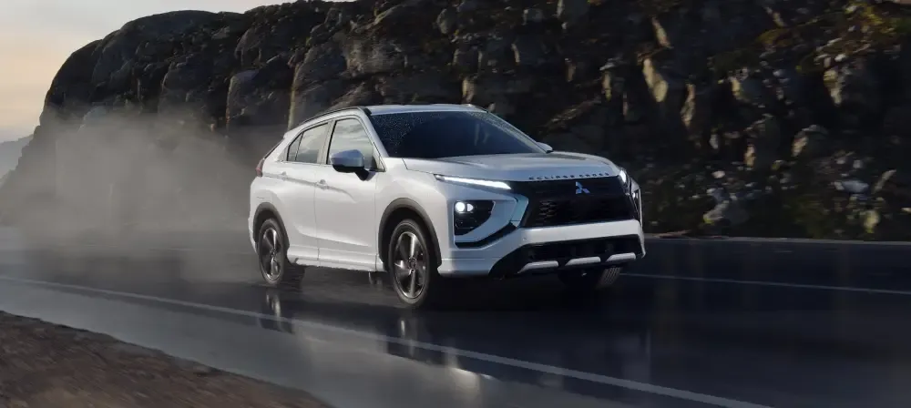 White Mitsubishi SUV driving on a wet mountain road