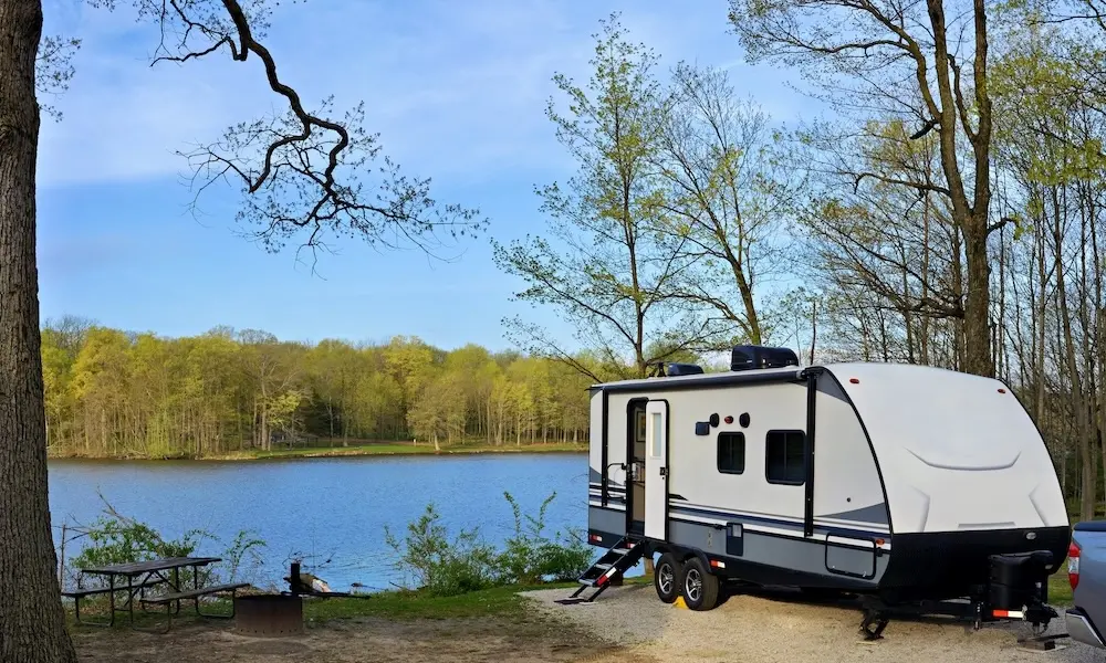 A white travel trailer parked near a lake