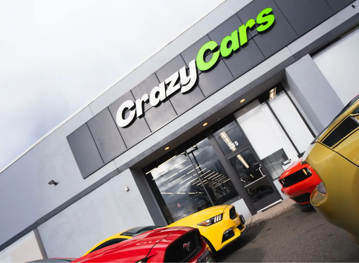 Exterior of the Crazy Cars dealership building with branded signage and parked vehicles in front.