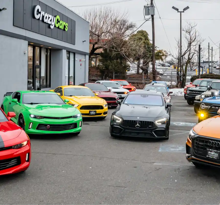 Inventory lineup parked outside the Crazy Cars dealership with multiple vehicles in front of the store.