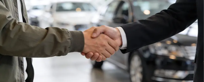 Salesperson shaking hands with a customer after a vehicle purchase at Dale Howard Auto Center