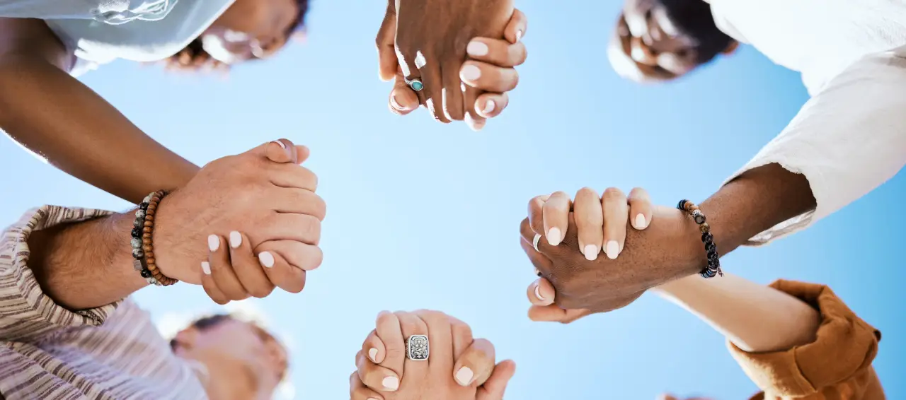 People joining hands together, representing community support at Dale Howard Auto Group