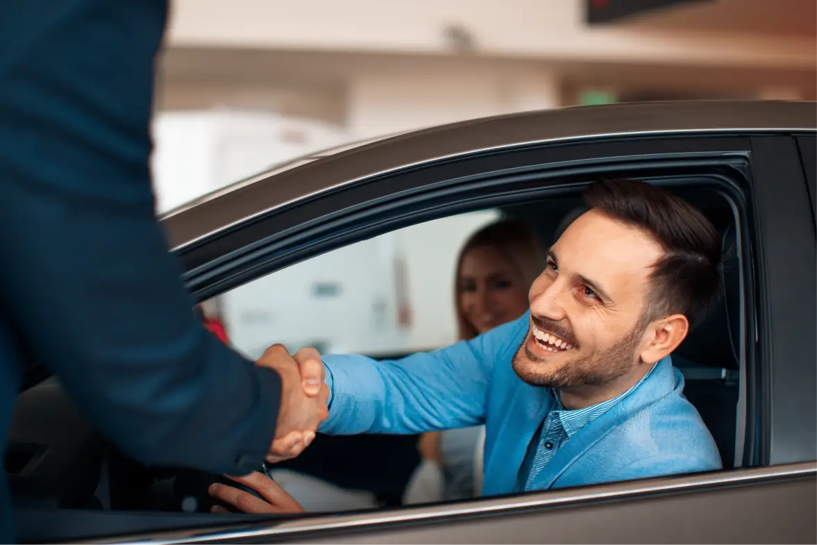 Smiling customer shaking hands with an Appleton Auto representative during a vehicle purchase.