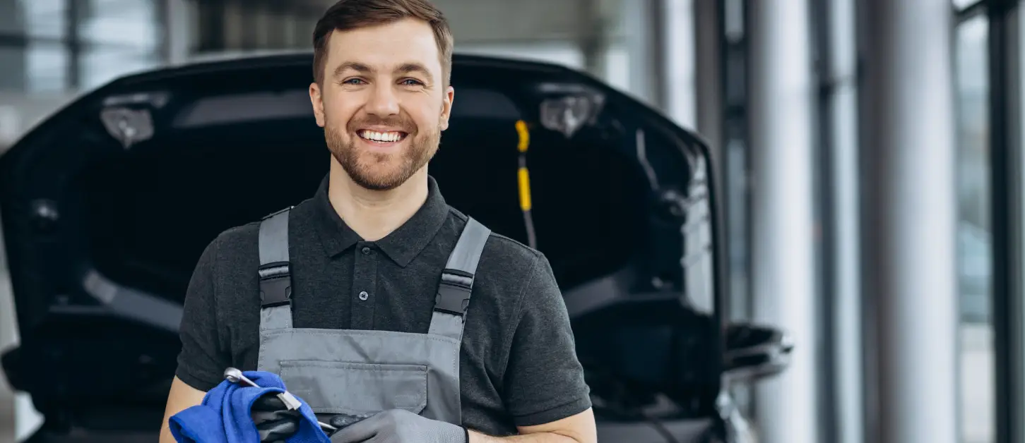 Smiling service technician standing in an auto repair shop at DNX Motors.