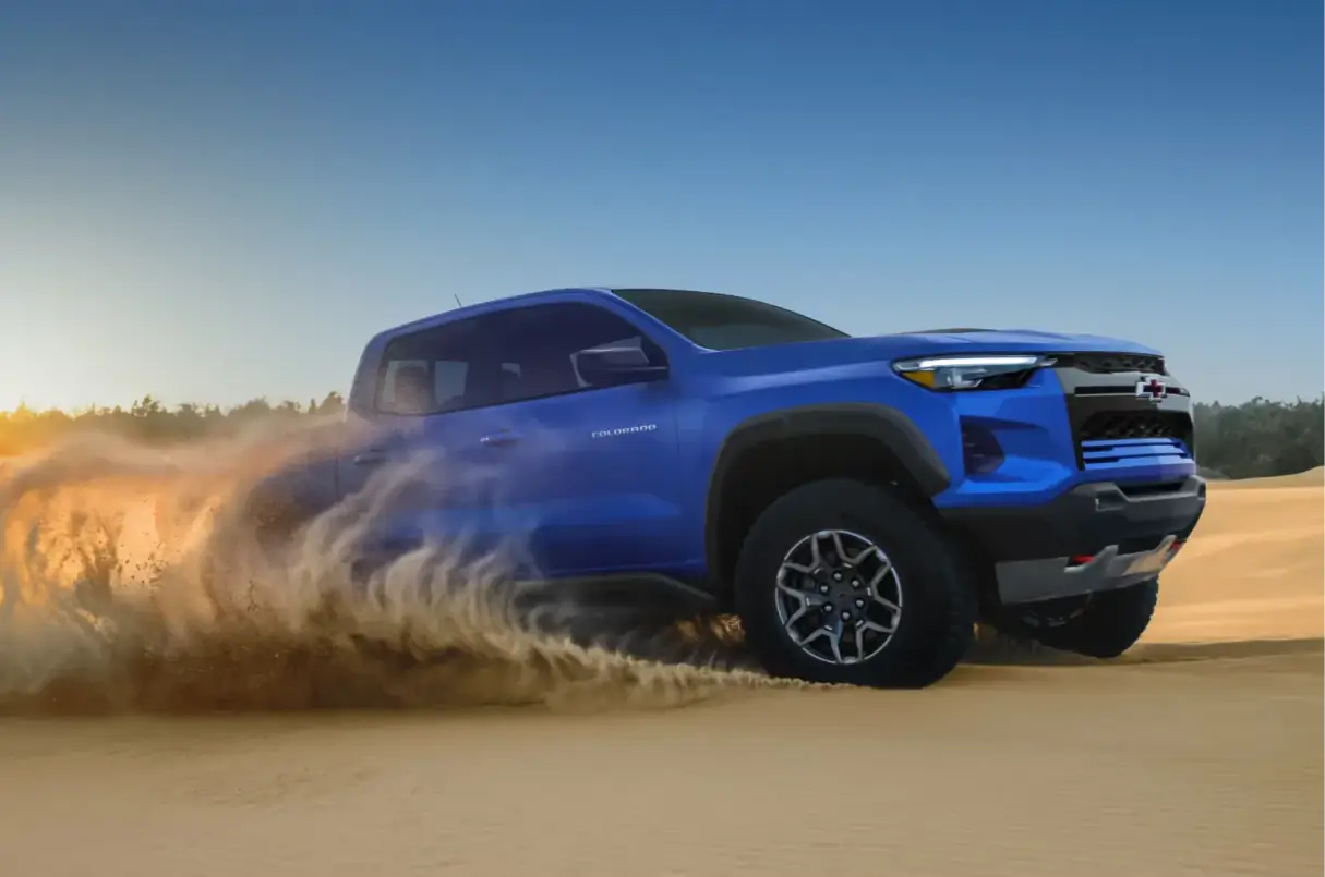 Blue Chevrolet Colorado driving through sand off-road
