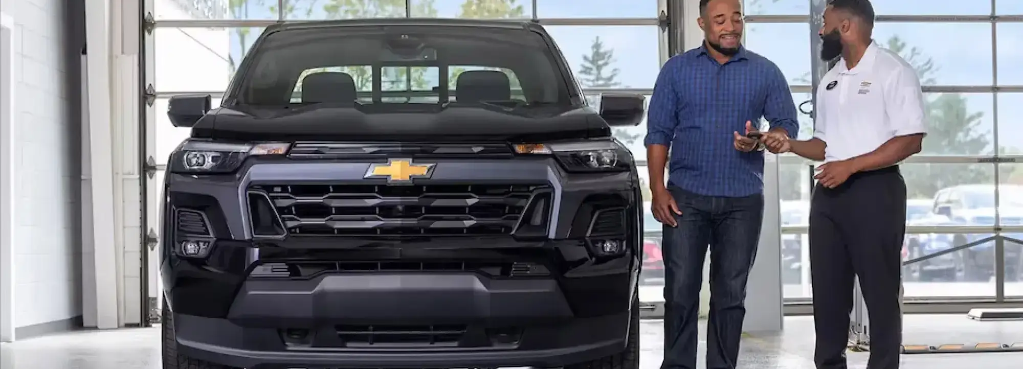 Chevrolet truck in a service center with a customer speaking to a service advisor