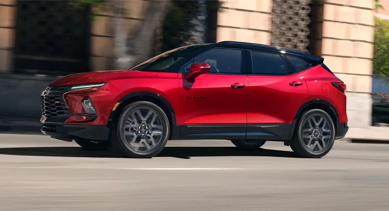 Red Chevrolet Blazer driving through a city street