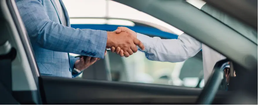 Customer shaking hands with a dealership representative after discussing financing