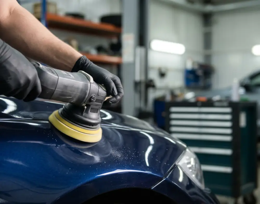 Technician polishing a vehicle body panel during collision repair