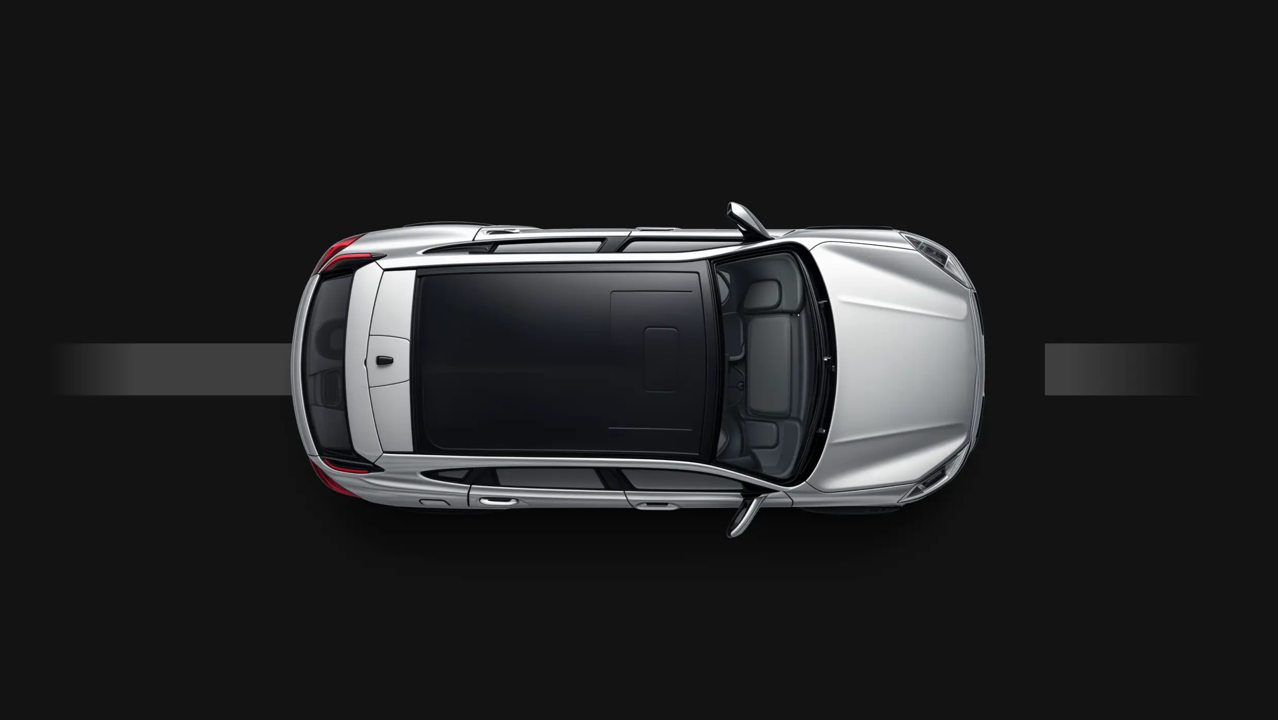 Top view of a silver vehicle driving on a dark road background.