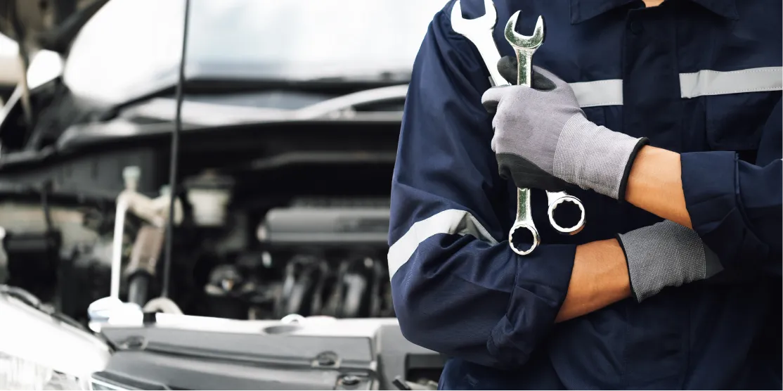 Automotive technician holding wrenches during vehicle service