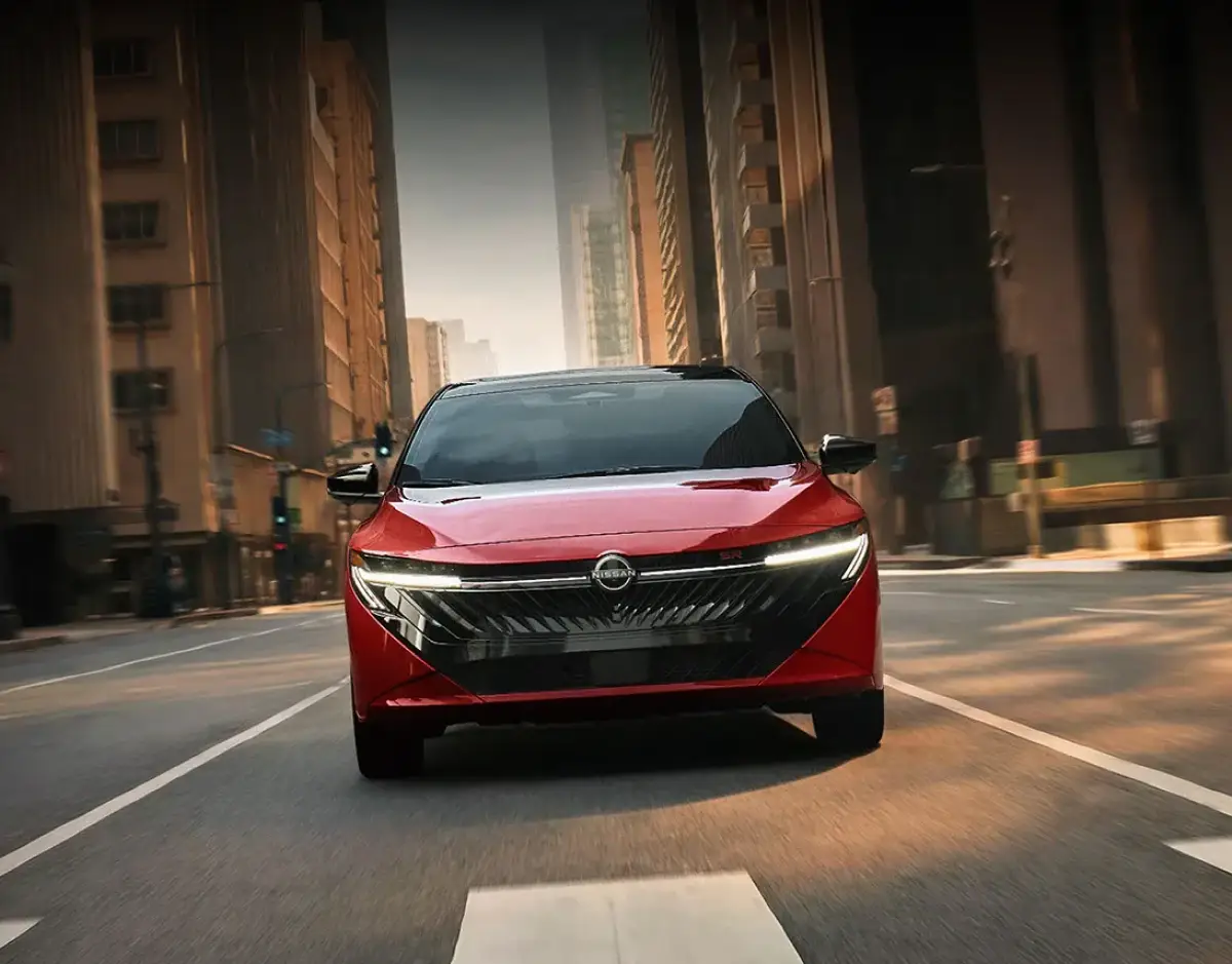 Red Nissan sedan driving through downtown city streets