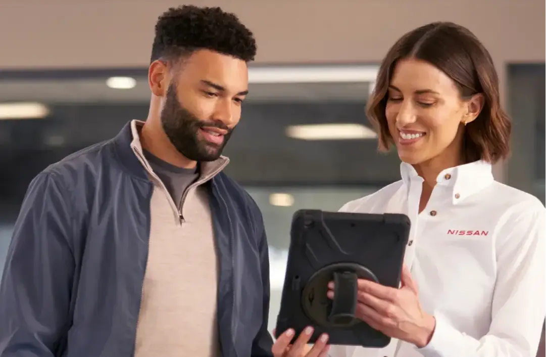 Nissan service advisor reviewing maintenance information with a customer on a tablet