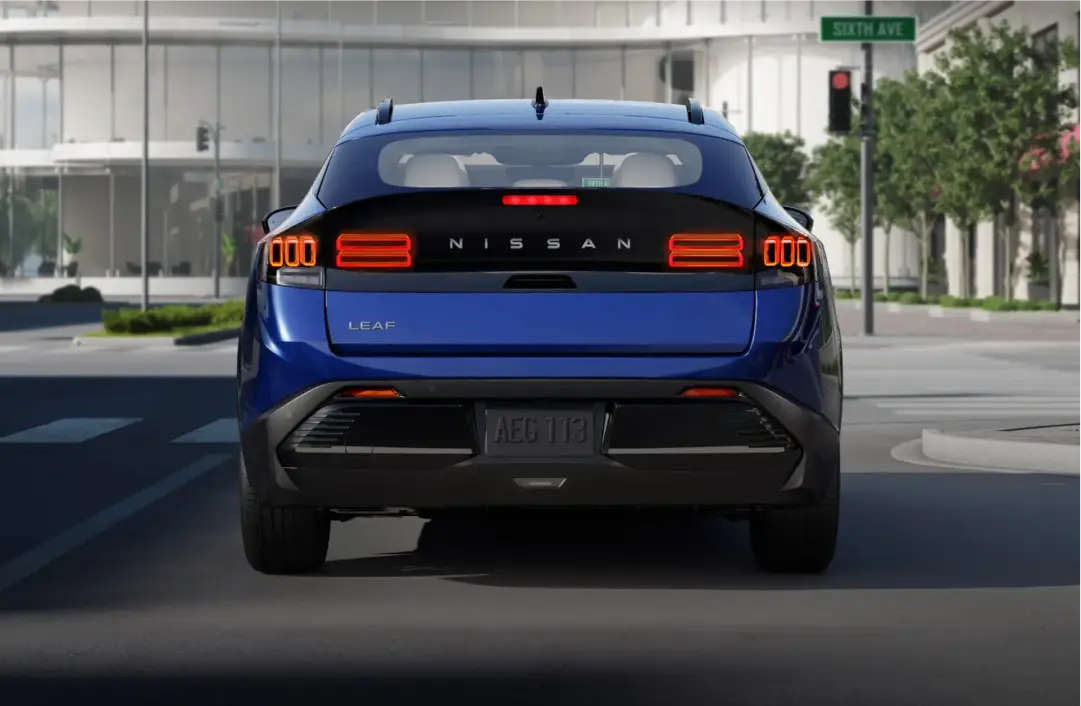 Rear view of a blue Nissan Leaf driving on a city street