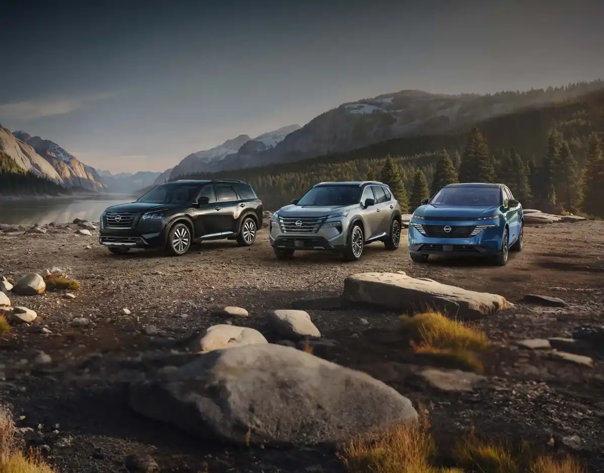 Three Nissan SUVs parked along a mountain lakeshore at dusk