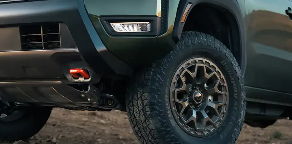 Close-up of a dark green Nissan SUV's front wheel and off-road tire