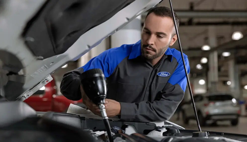 Ford technician using a power tool under the hood