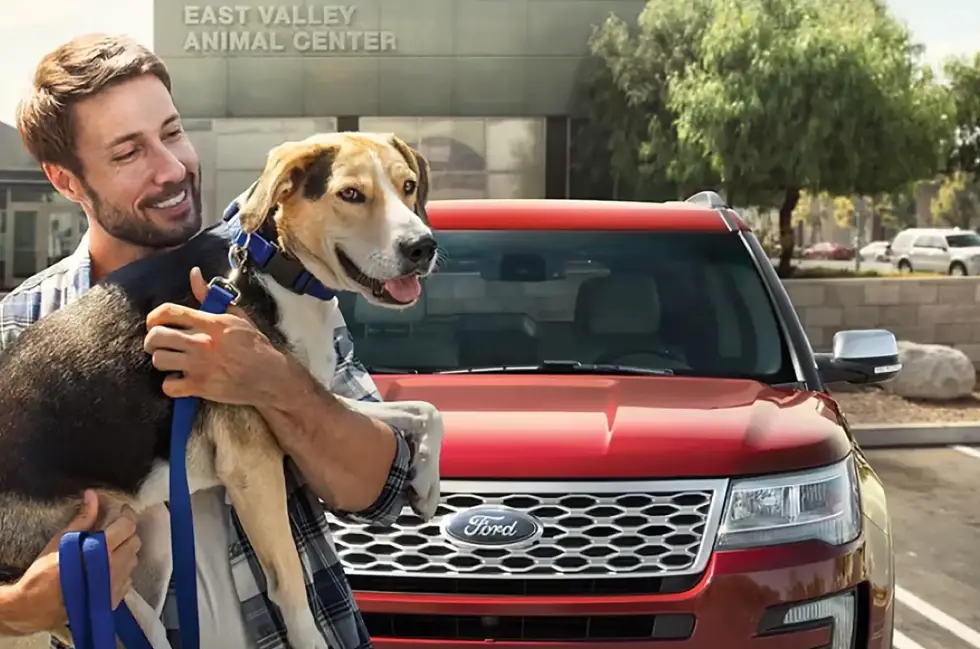 Man with dog beside a red Ford Expedition