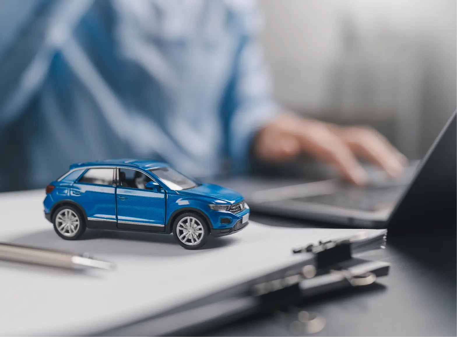 Customer browsing vehicle options online with a model car on desk.