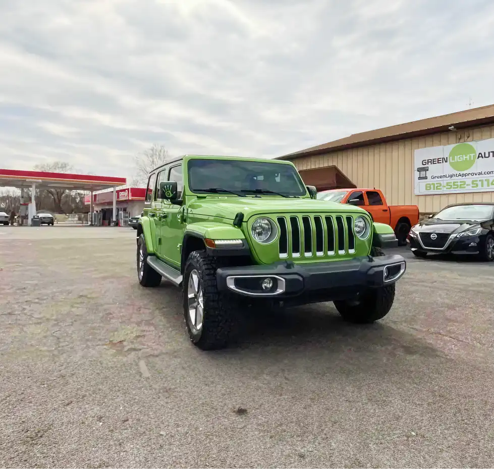 Green Jeep SUV parked outside Green Light Auto dealership.