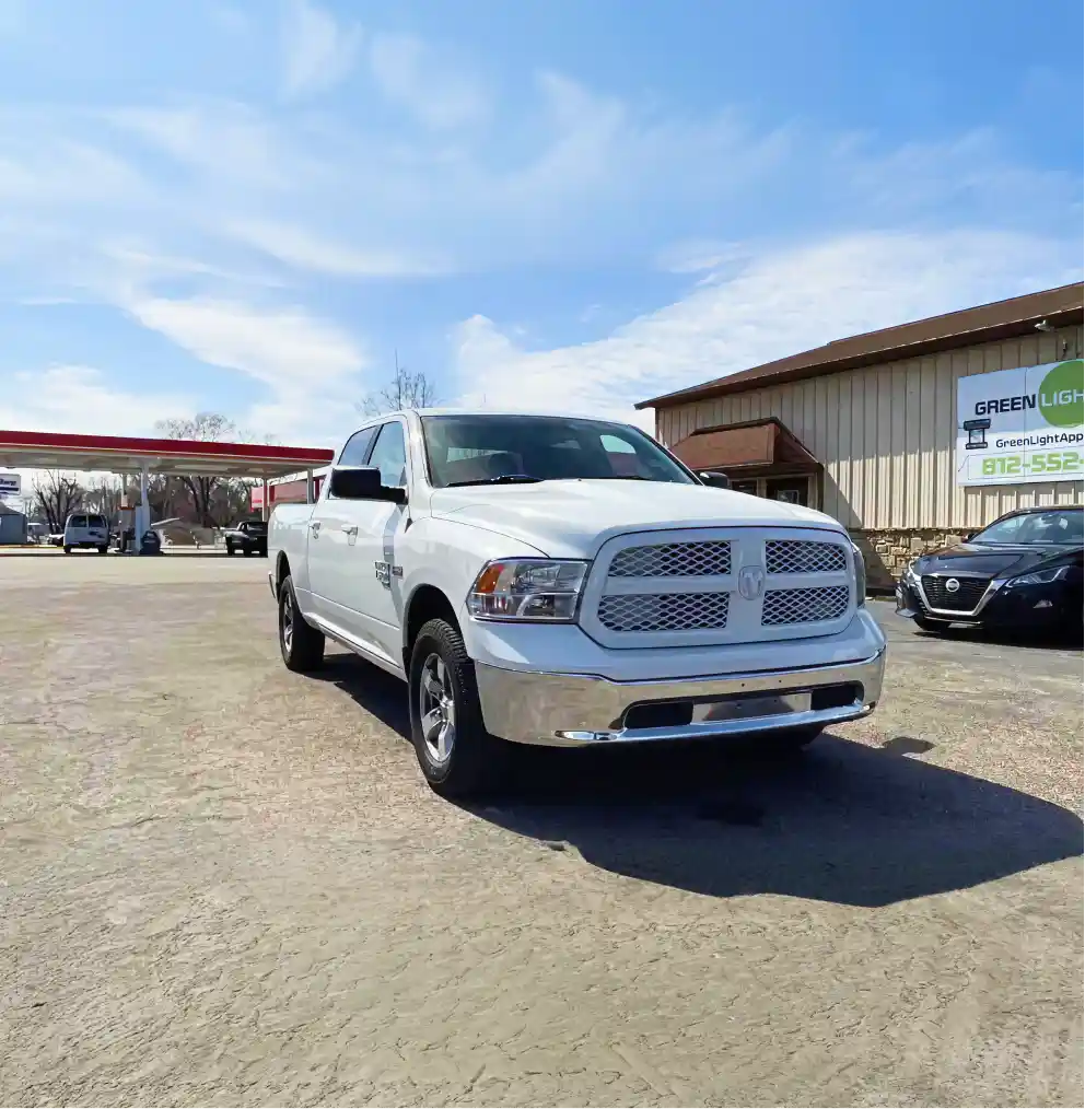 White pickup truck parked outside Green Light Auto dealership.