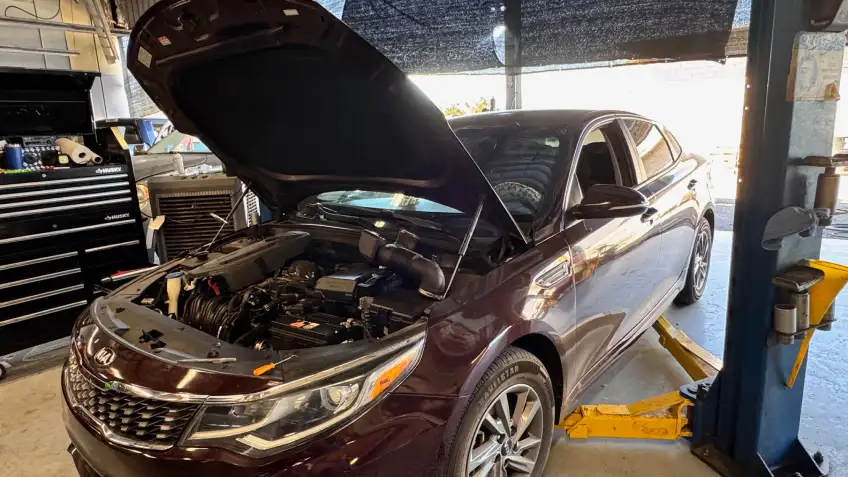 Technician performing maintenance on a vehicle at Ideal Cars repair bay in Mesa, AZ.