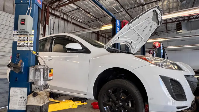 Car being serviced on a lift at Ideal Cars in Mesa, AZ.