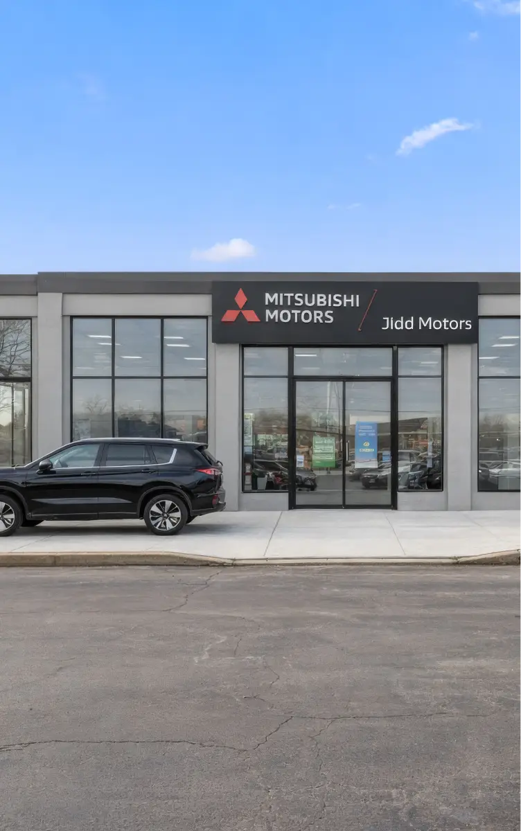 Front entrance of Jidd Motors Mitsubishi dealership with vehicles parked outside.