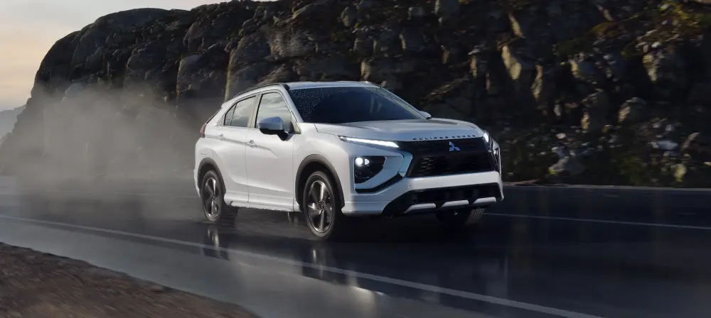 White Mitsubishi SUV driving on a wet mountain road
