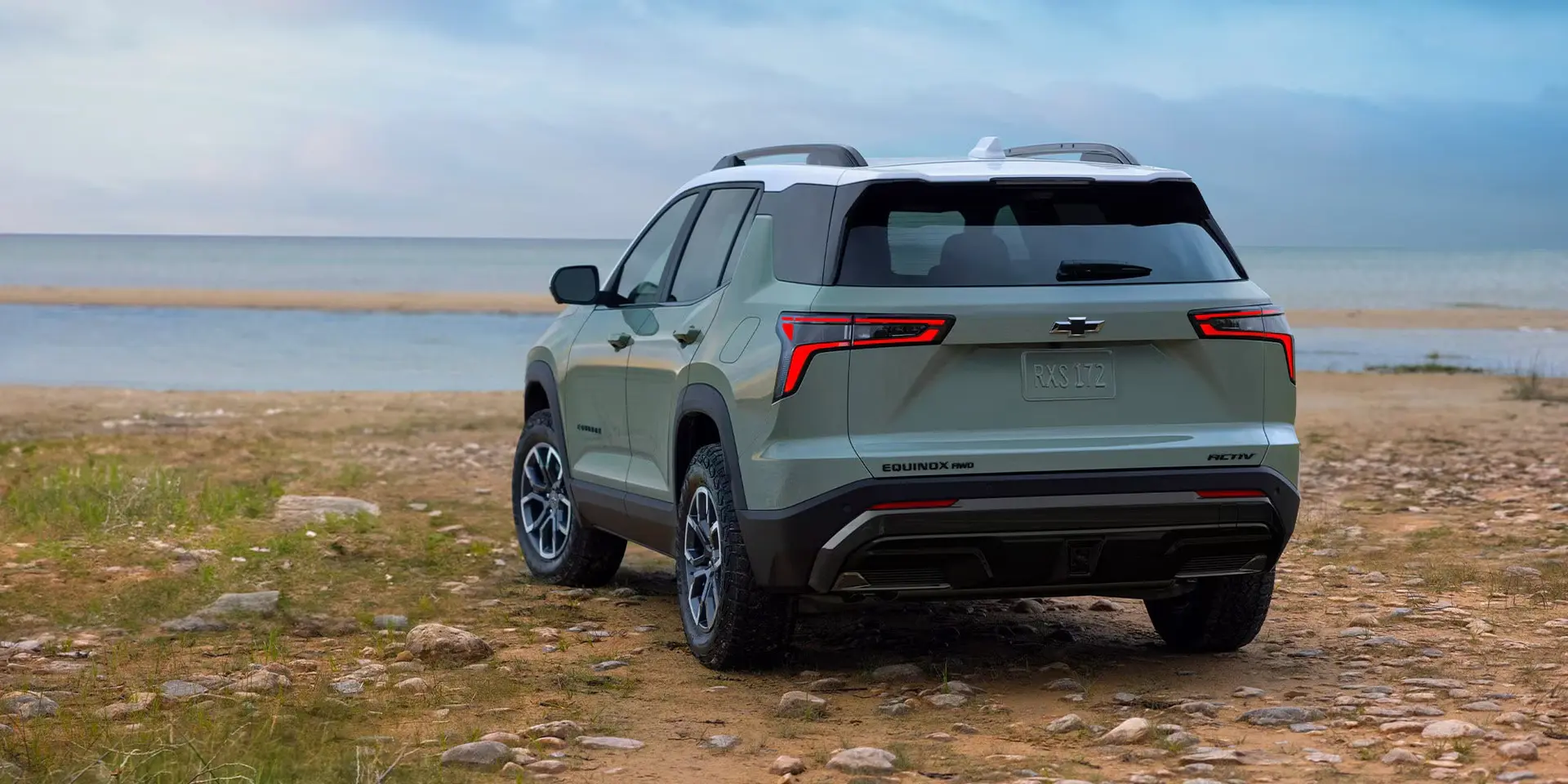 A green suv sitting parked off-road.