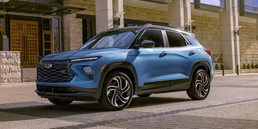A blue trailblazer sitting in the road.