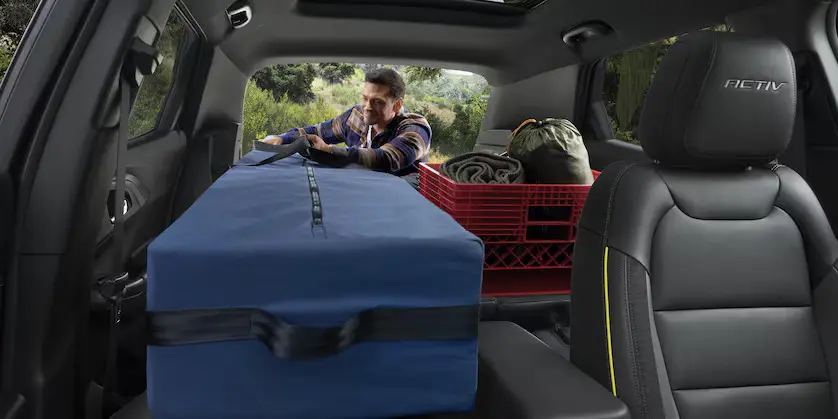 A man putting cargo into the back of a trailblazer.