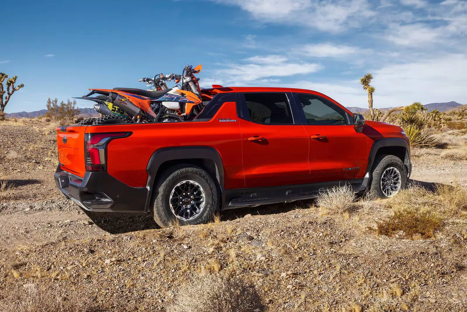 A red truck carrying two dirt bikes.