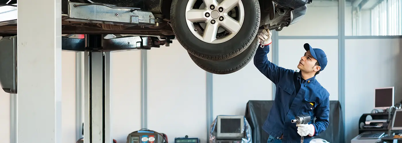 A man looking under a car.