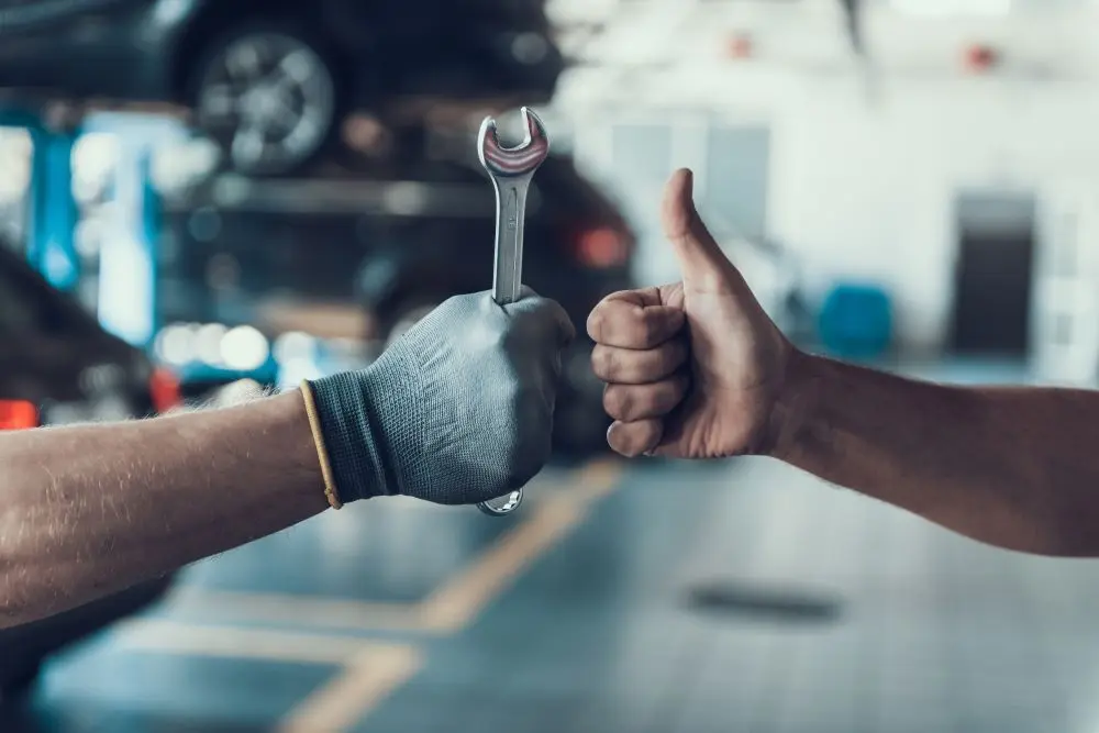 One hand holding its thumb up the other holding a wrench.