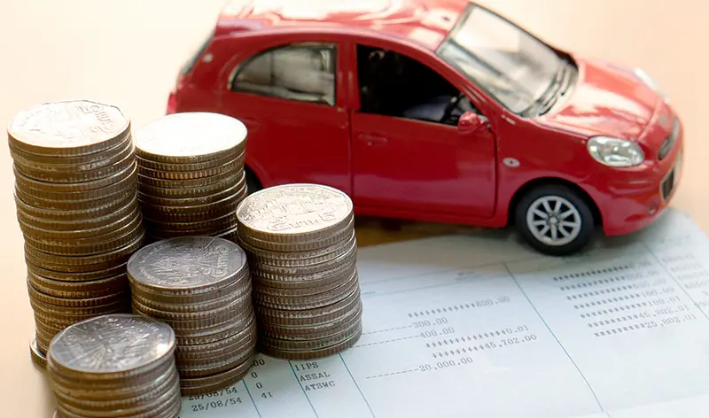 a red car next to a stack of quarters