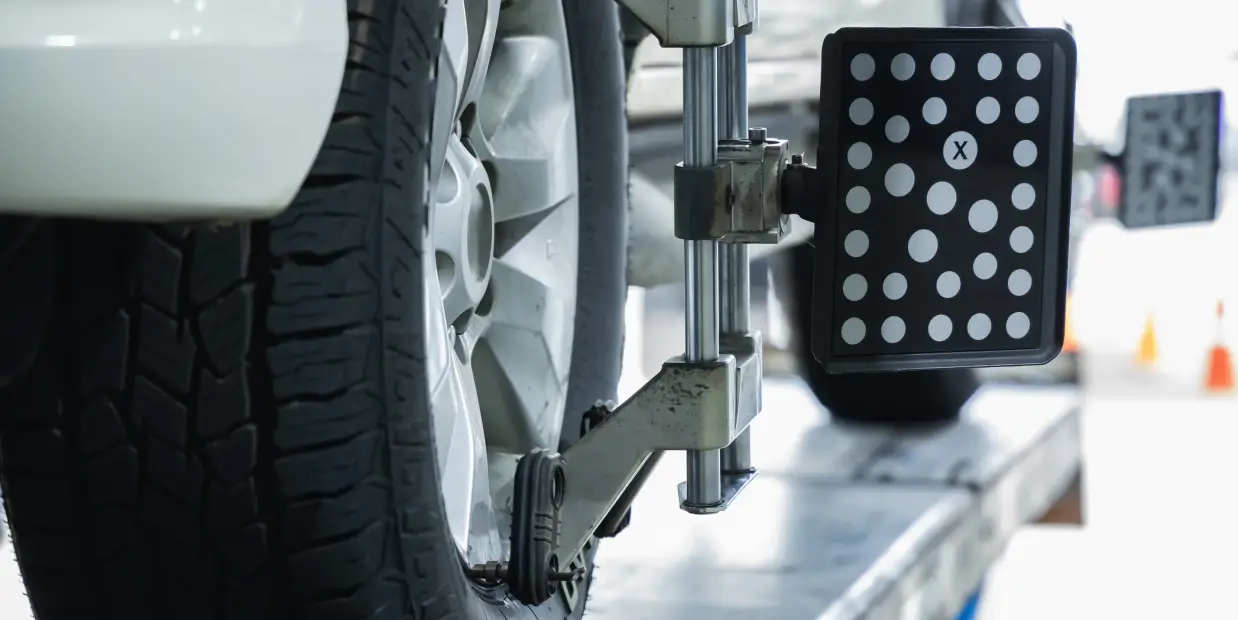 Vehicle undergoing wheel alignment service at an auto repair shop