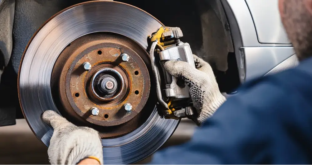 Mechanic inspecting a vehicle’s brake rotor and caliper