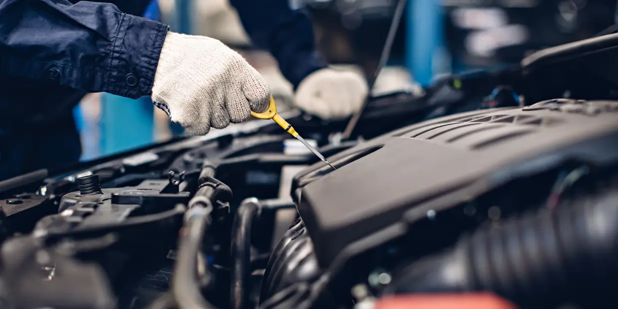 Mechanic checking a vehicle’s oil level with a dipstick