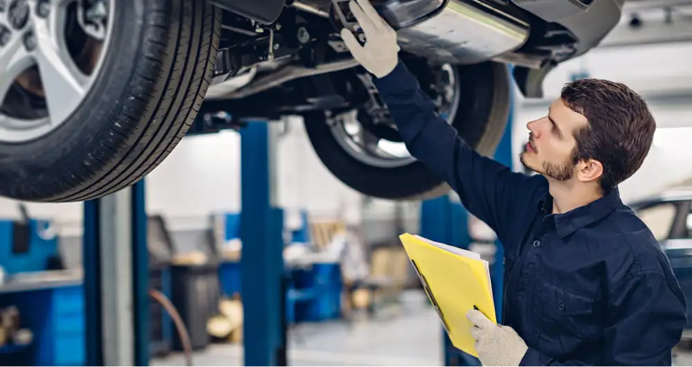 Technician inspecting the underside of a vehicle on a service lift