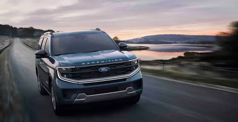 Ford Expedition driving along a coastal road at sunset