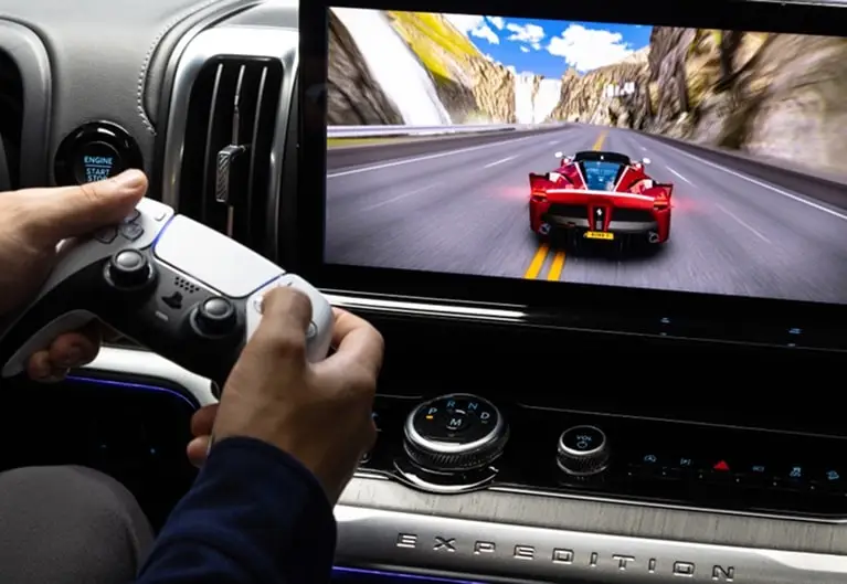 Passenger playing a racing game on a Ford center touchscreen with a game controller