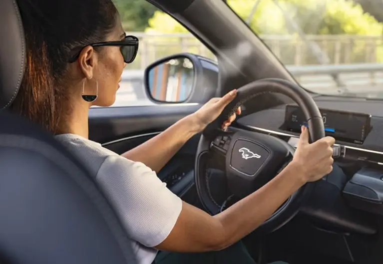 Driver behind the wheel of a Ford Mustang Mach-E crossing a bridge
